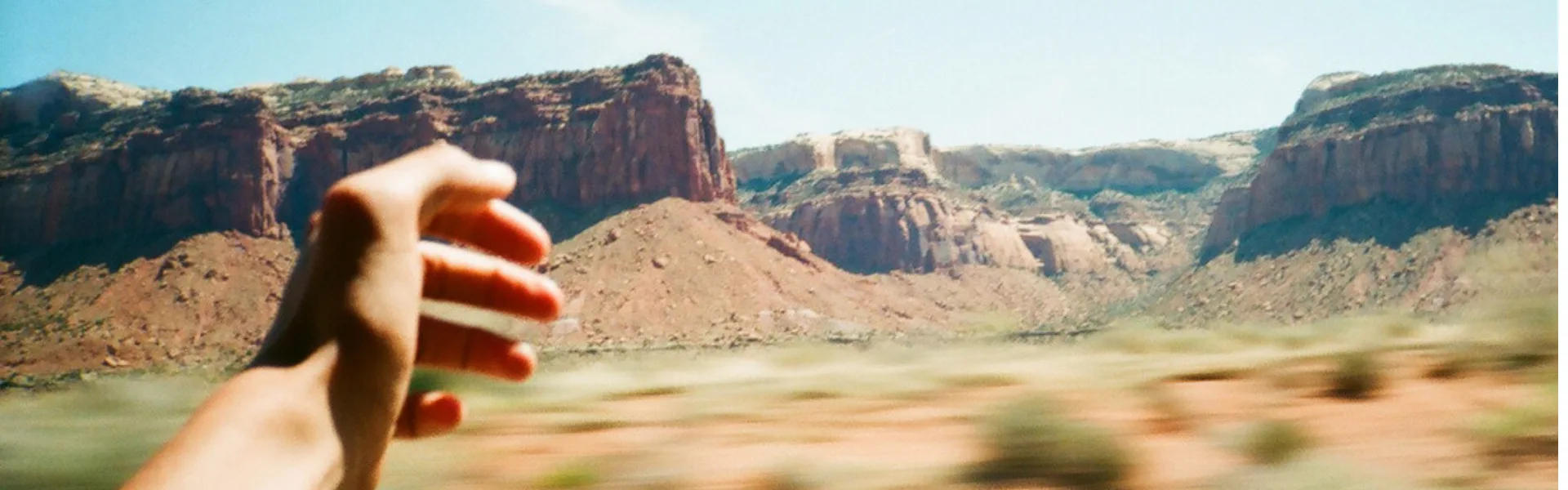 Persona disfrutando del paisaje desértico con el brazo fuera del coche, símbolo de libertad y bienestar auditivo